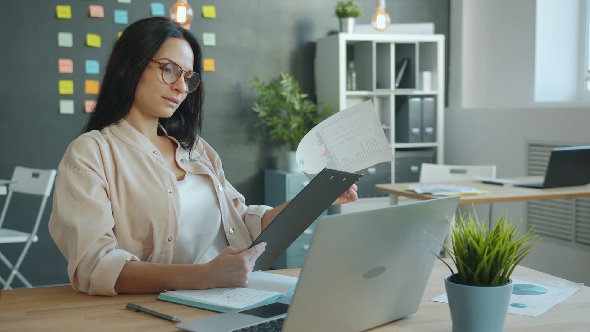 Person reviewing and annotating documents at a desk — carefully reading through a strata report